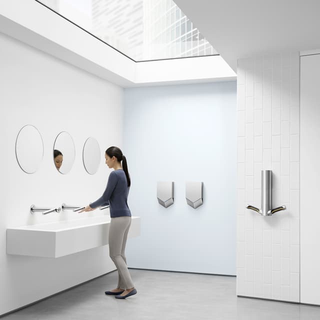 Kvinne vasker hender i vask ved siden av Dyson Airblade