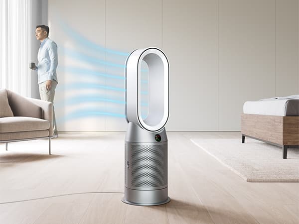 Man som står framför fönstret med en Dyson Hot&Cool-luftrenare i förgrunden.