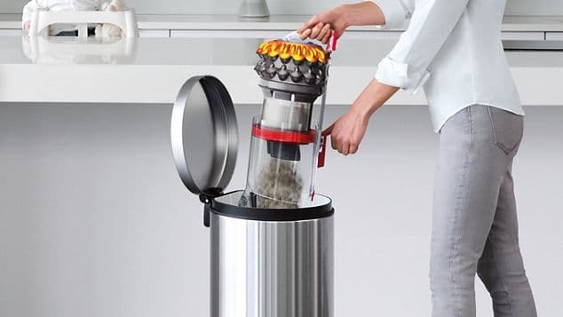 En person som tømmer beholderen på Dyson-støvsuger