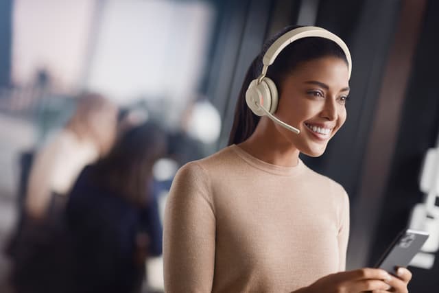 Jabra - Kvinna med beige Evolve2 65 hörlurar på kontor