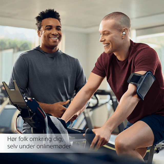 Mand på motionscykel ler til mand ved siden af