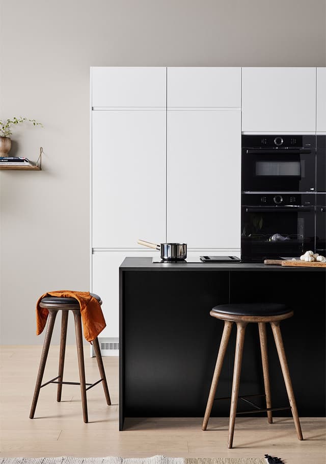 Epoq Pure Matt Black kjøkkenøy med hvite skap i bakgrunnen og to barkrakker rundt på øya