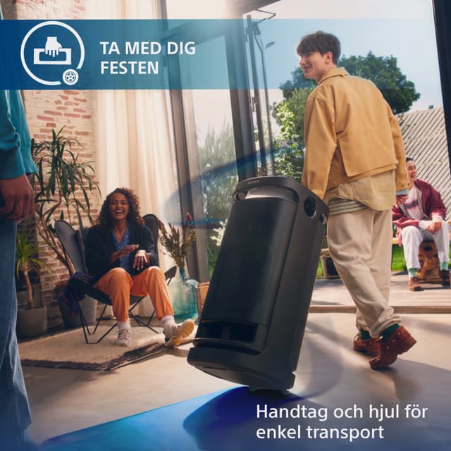 Glada ungdomar i ett vardagsrum med en balkongdörr som står öppen och en kille som drar en SRS-XV900 bakom sig på väg ut