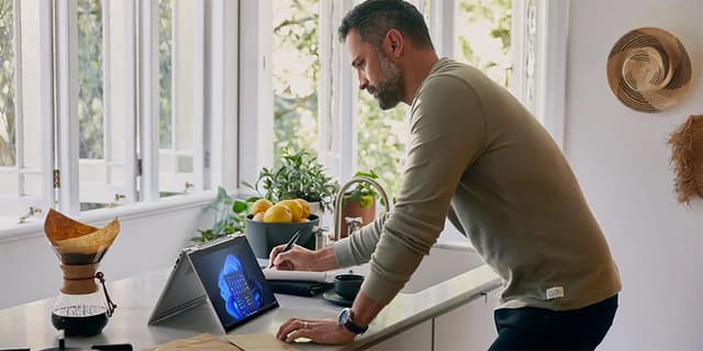 Man at a kitchen island in front of a folded HP EliteBook