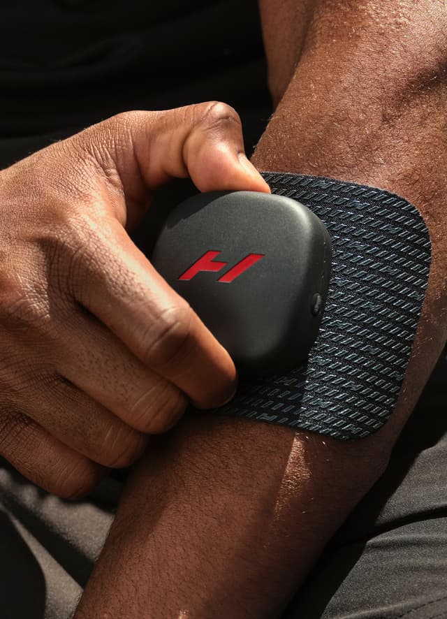 En mand, der bruger et Hyperice Venom Go-massageplaster på sin arm