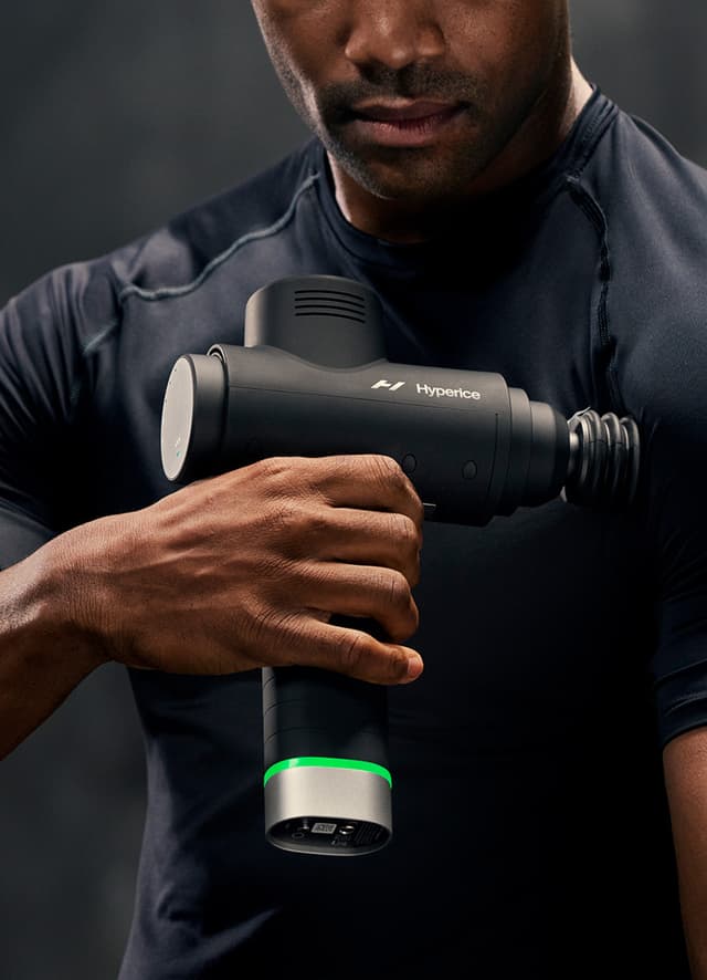 mand, der bruger en Hyperice Hypervolt 2 Pro massagepistol på sine muskler