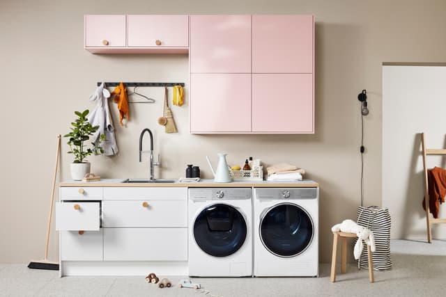 EPOQ - Trend - Laundry room - Utility room - Light pink and white - Washing machine - Tumble dryer - Faucet - Sink - Linoleum countertop - Chair - Open drawer - Green plant - Wooden Handles