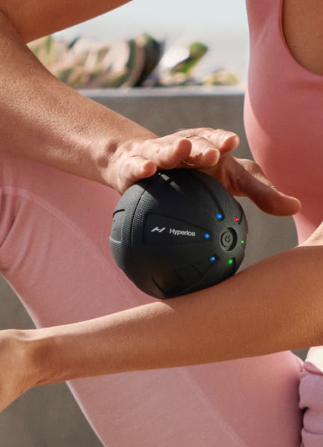 En kvinne som bruke en Hyperice Hypersphere massasjeball