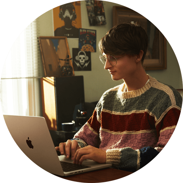 Ung person der sidder ved en åben Macbook Pro
