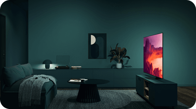 Samsung OLED TV i en mørk stue med et lyst billede på skærmen