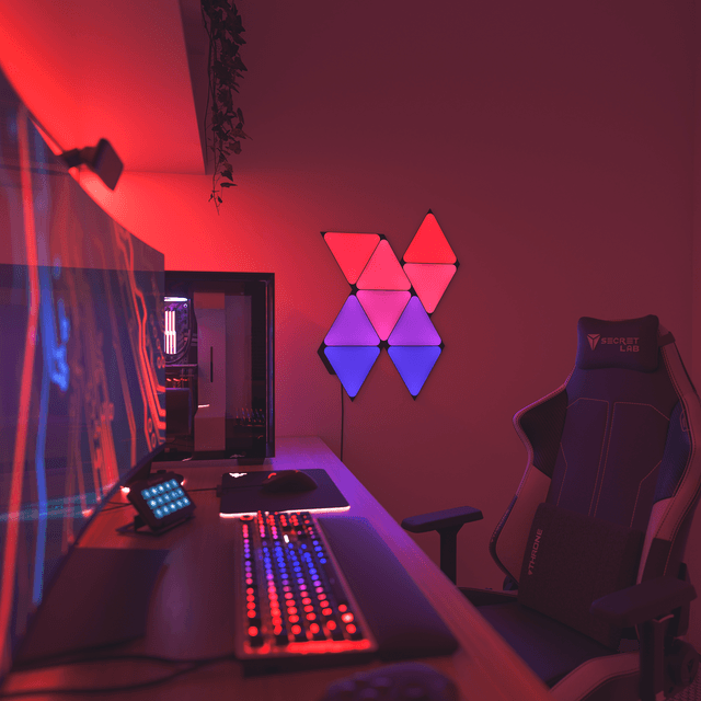 Nanoleaf Black Triangles smart  lyspanel med røde og lilla lys ved siden av gamingoppsett