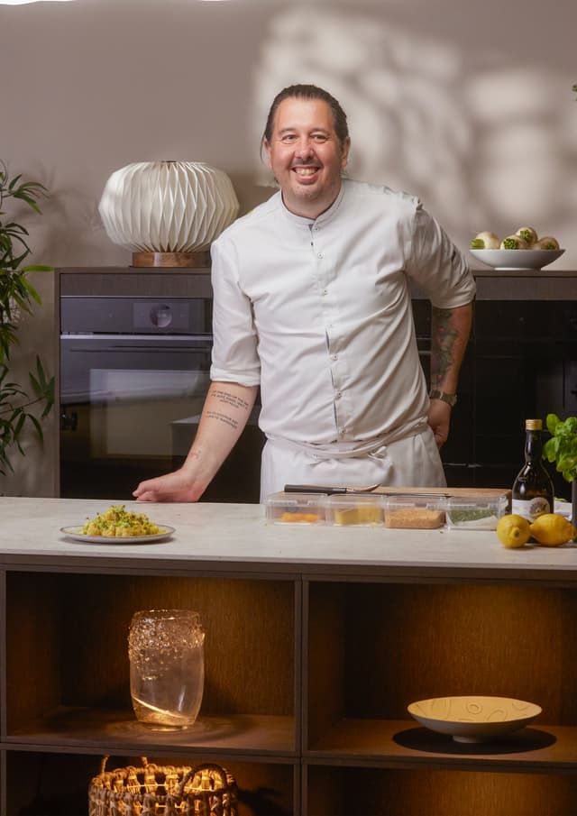 Chef standing in front of Bosch accent line ovens showing off the dished he has made