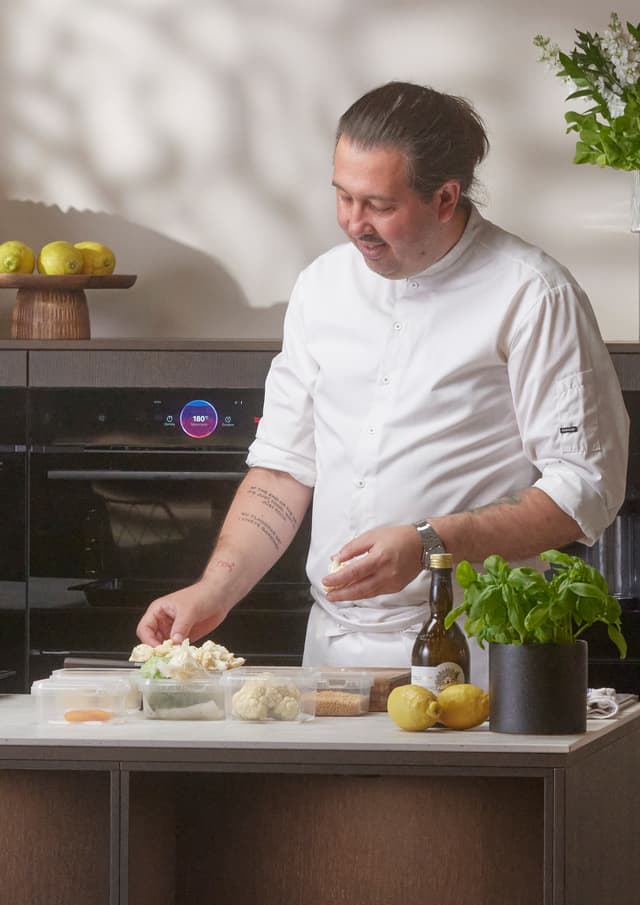 Chef standing in front of Bosch accent line ovens preparing dishes