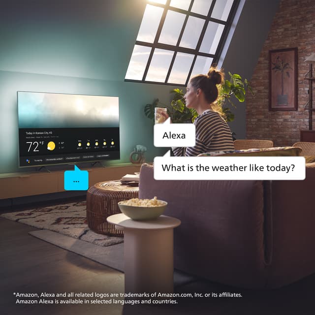 Nainen istuu olohuoneessaan ja antaa äänikomentoja Philips TV:n Google Alexalle