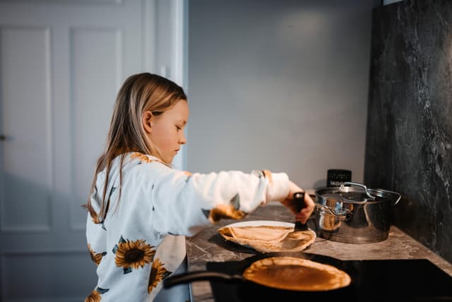 Pannukakkupäivä 2024 - Tyttö tekee pannukakkuja keittiössä