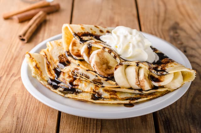 Lettupäivä 2024 - Crepe-ohukaiset lautasella, jossa on banaania, kermavaahtoa ja suklaata