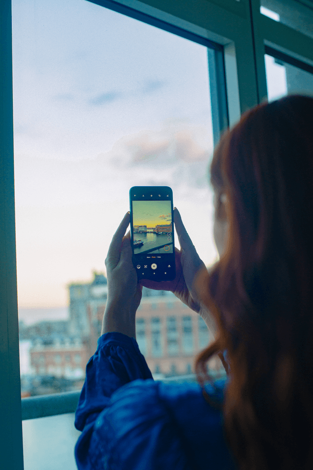 Fairphone 4-telefon i hendene på en jente som tar bilde gjennom et vindu