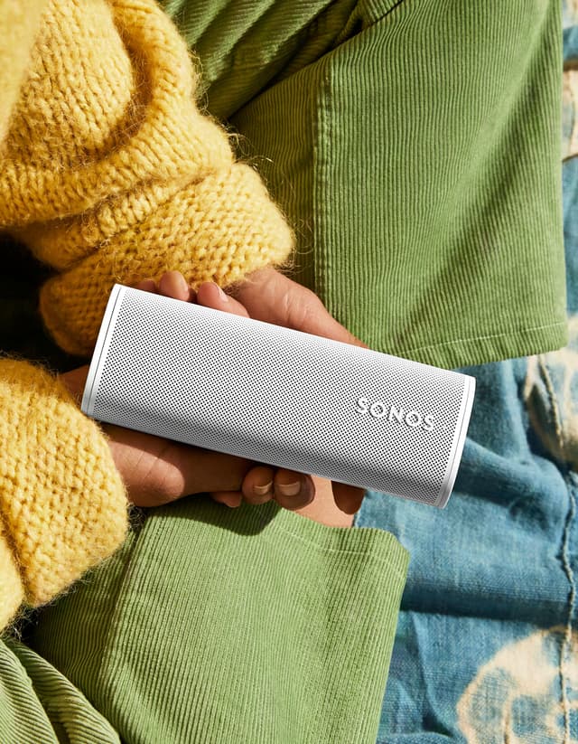 Sonos Roam 2 i hendene på en person med grønne bukser