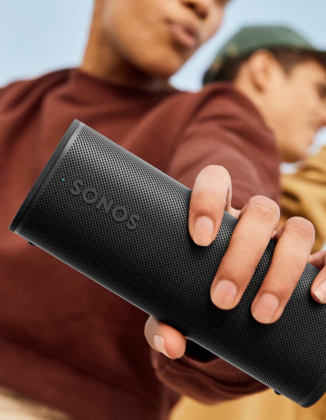 En person der holder en Sonos-højttaler i hånden