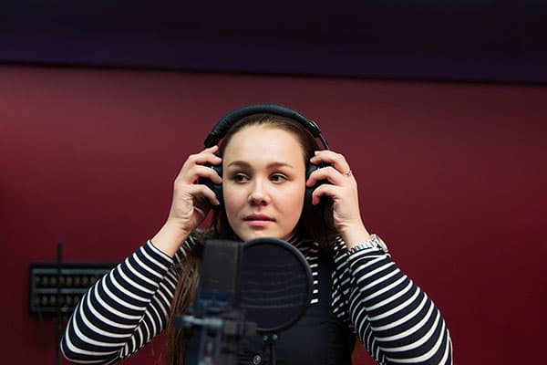 en kvinne med hodetelefoner på spiller inn en podcast