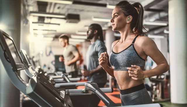 Kvinne som løper på tredemølle med Jabra Elite 8 Active G2 i ørene
