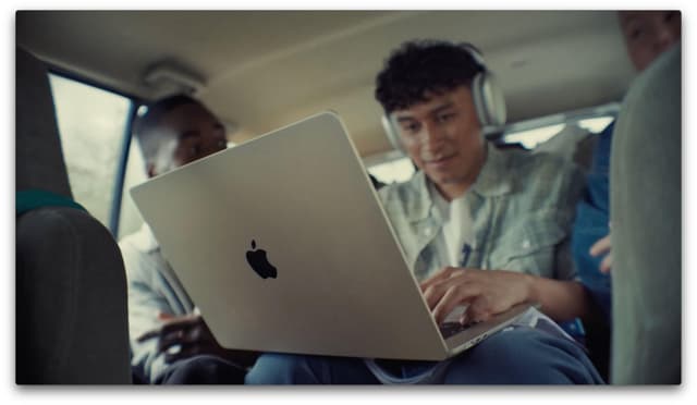 Nærbilde av ung student i baksetet av bilen med MacBook Air på fanget og AirPods Max på
