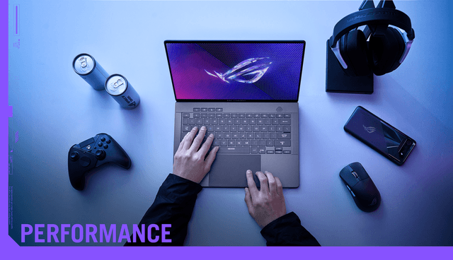 Asus ROG ZEPHYRUS G14 laptop på et bord med kontroll, hodetelefoner, mus og mobiltelefon