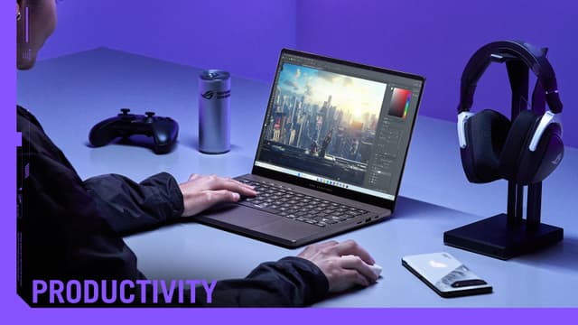 Person som använder ROG ZEPHYRUS G14 laptop och kontroller, hörlurar och mobiltelefon bredvid.
