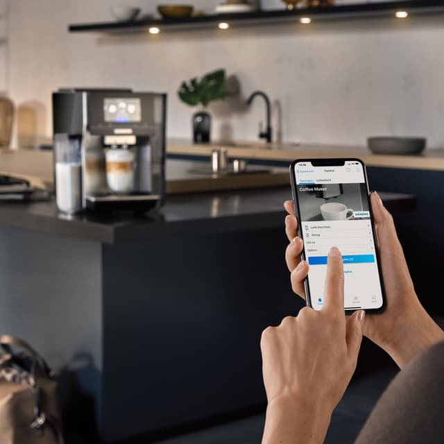 Person styrer Siemens EQ700 kaffemaskin med HomeConnect-appen
