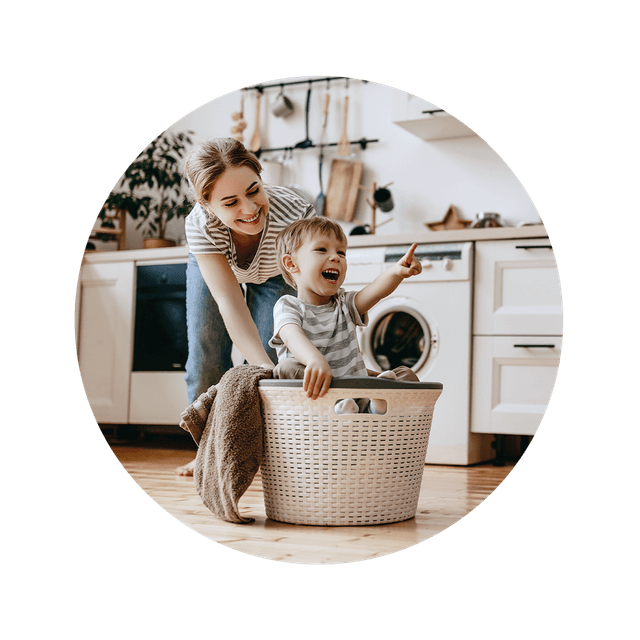 Mother and child in the kitchen playing with laundry basket
