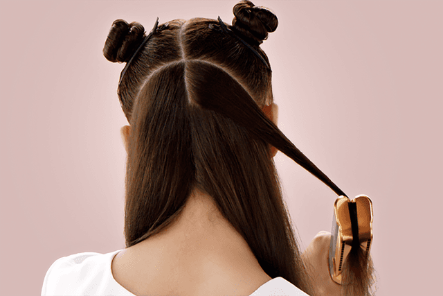 Dark haired girl using Dyson Airstrait™ straightener to style her hair