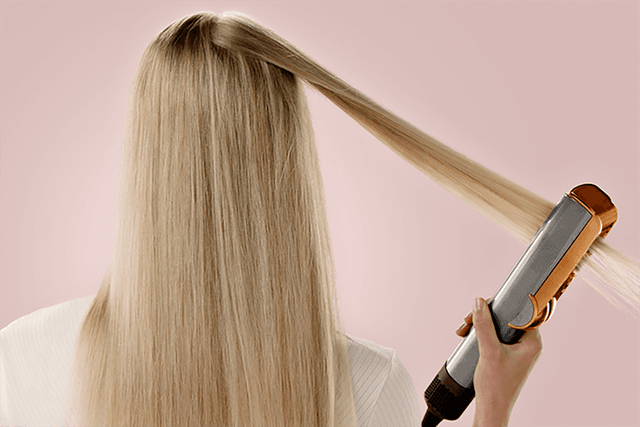 Light haired girl using Dyson Airstrait™ straightener to style her hair