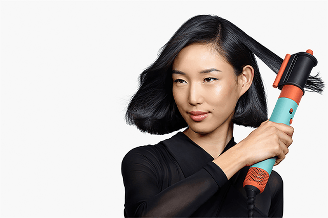 Mørkhåret kvinde bruger Dyson Airwrap™ multi-styler og føntørrer til at tørre og glatte håret - føntørrer + Flyaway smoother
