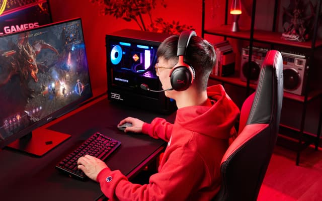Gaming - Poika punamustat HyperX Cloud III S Wireless -pelikuulokkeet päässään pelitietokoneen edessä