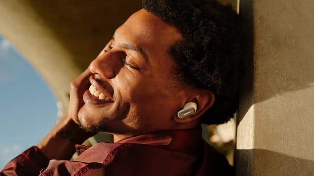 Musiikkia kuunteleva mies valkoiset Bose QuietComfort Ultra Earbuds -nappikuulokkeet päässään