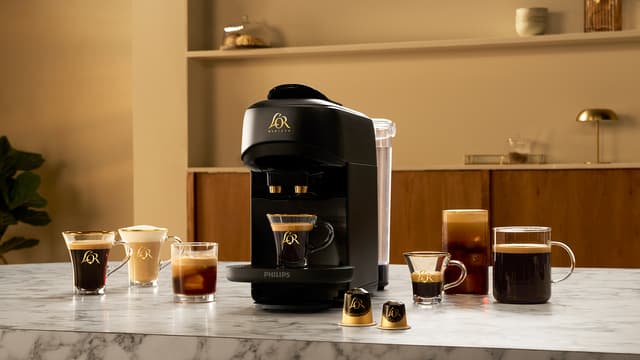 L’Or Absolu capsule machine on kitchen counter surrounded by coffee cups
