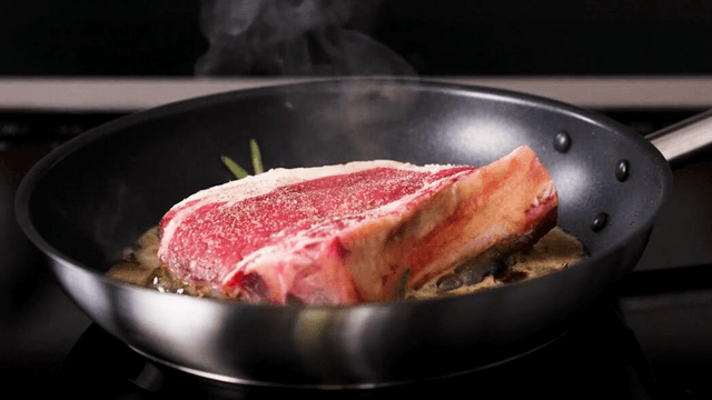 Juicy steak being fried on a frying pan