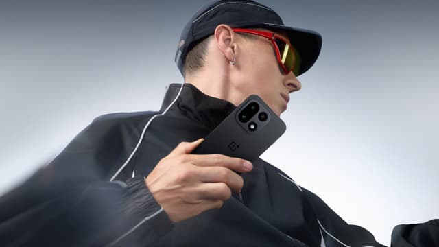 Urheiluvaatteisiin pukeutunut mies OnePlus 15 -puhelin kädessään