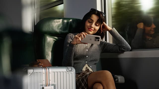 Junassa matkustava nainen katselee sisältöä OnePlus 15 -puhelimeltaan
