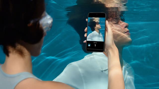 Nainen ottaa kuvaa miehestä OnePlus 15 -puhelimella veden alla