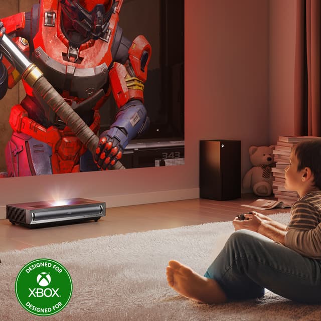 Lapsi pelaa Xboxia ja heijastaa pelin valkokankaalle Hisense - PX3 Pro -projektorilla