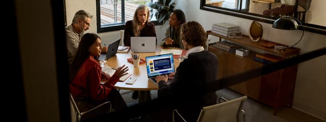 Apple - B2B - People around a table working with Apple products