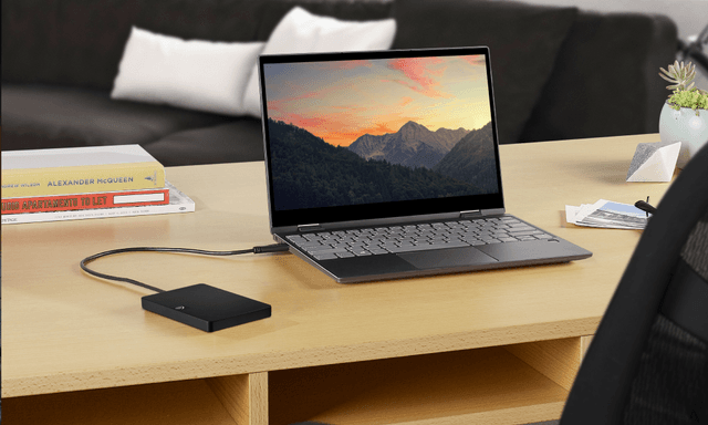 Bærbar Seagate harddisk tilkoblet laptop på skrivebord i tre