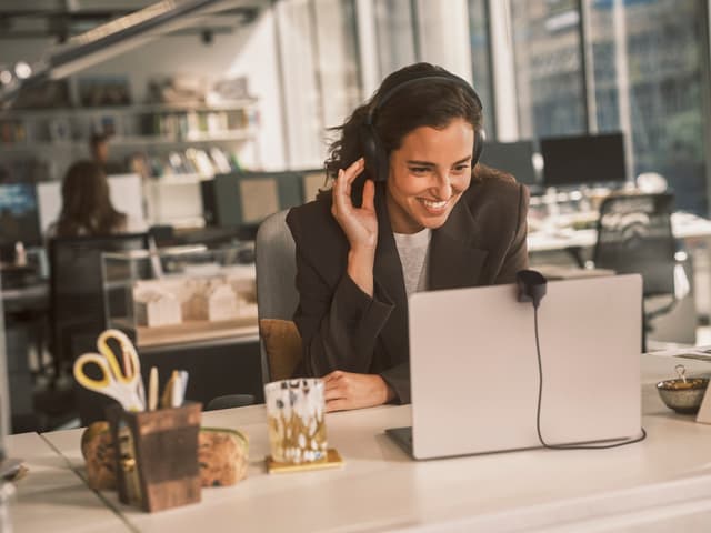 En kvinne i et videomøte på et kontor med Jabra Evolve3 85-headset på.