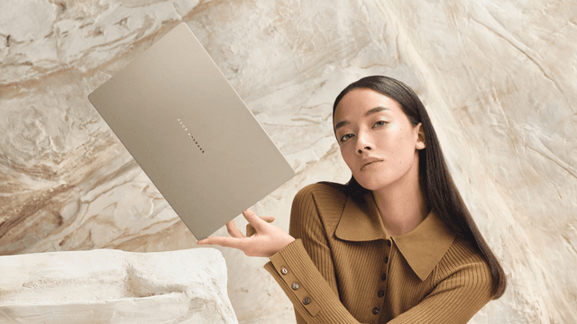 Kvinde holder en slank Zenbook A16 laptop foran en stenvæg 