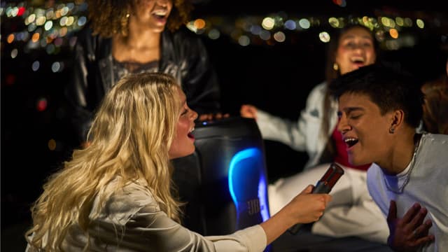 En gruppe venner synger med til JBL PartyBox 130-høyttaleren.
