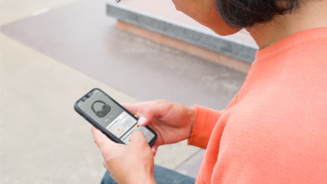 En person justerar inställningarna till hörlurarna via JBL Headphones-appen.