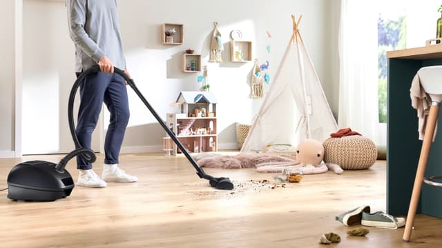  Mies imuroi murusia puulattialta Bosch Series 4 -pölynimurilla