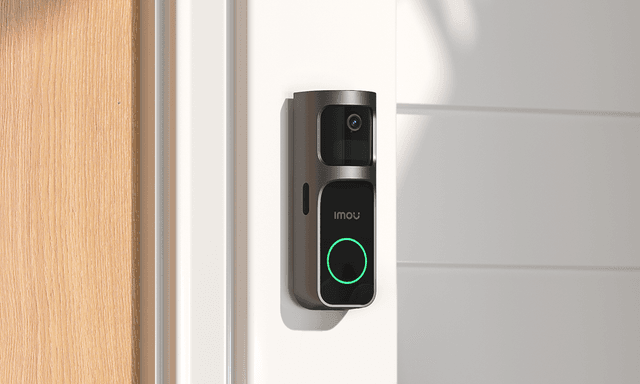 Imou Doorbell 2S placerad utomhus på en vägg bredvid en ytterdörr.