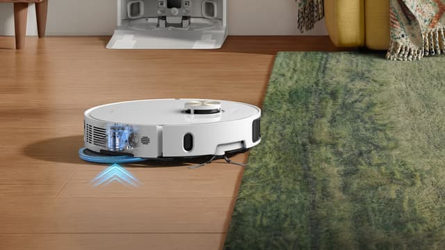 En Dreame L50 Ultra AE-rengjøringsrobot skifter modus idet den kjører fra parkett over på et teppe.